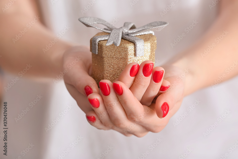 Woman with beautiful manicure holding gift, closeup