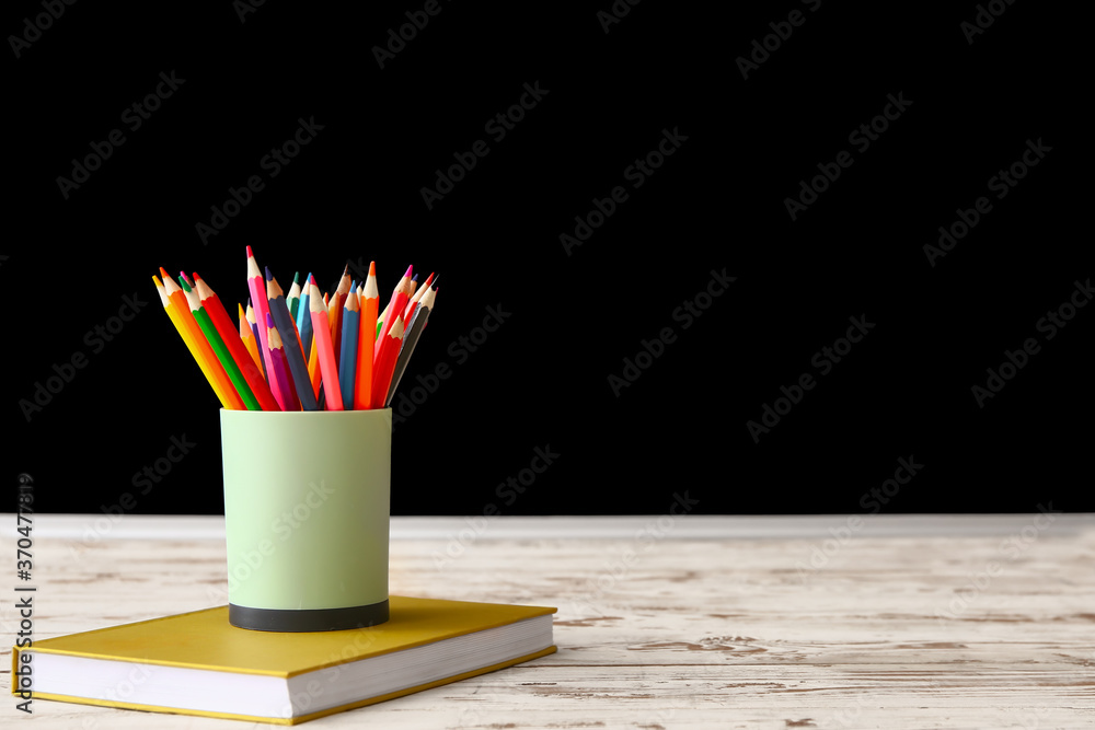 Set of pencils and book on table