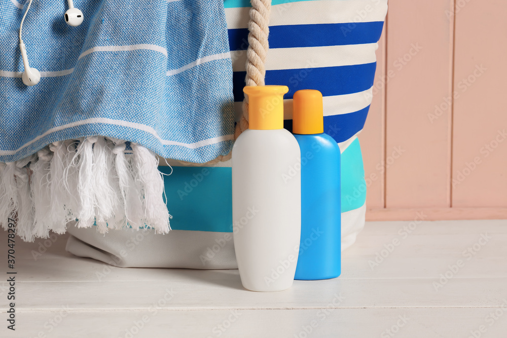 Beach bag with sunscreen cream on table