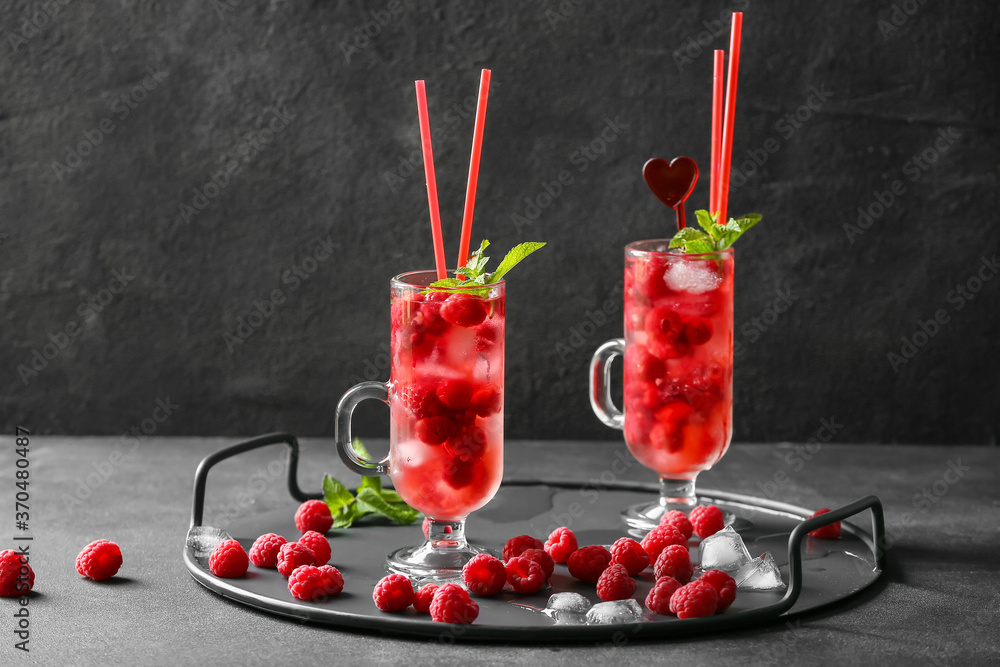 Cups of cold raspberry tea on dark background