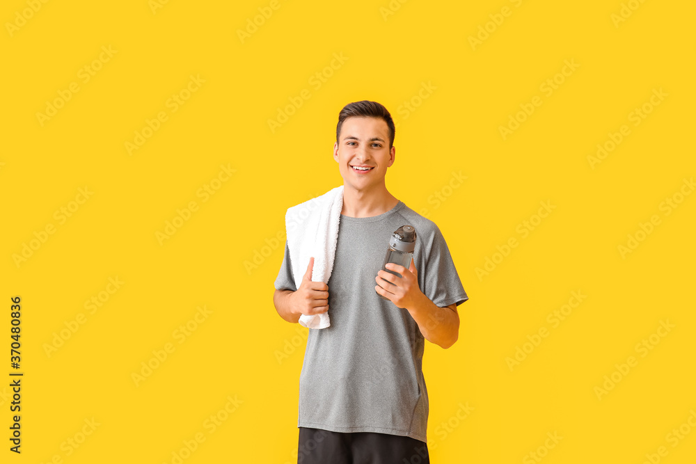 Sporty young man with bottle of water on color background