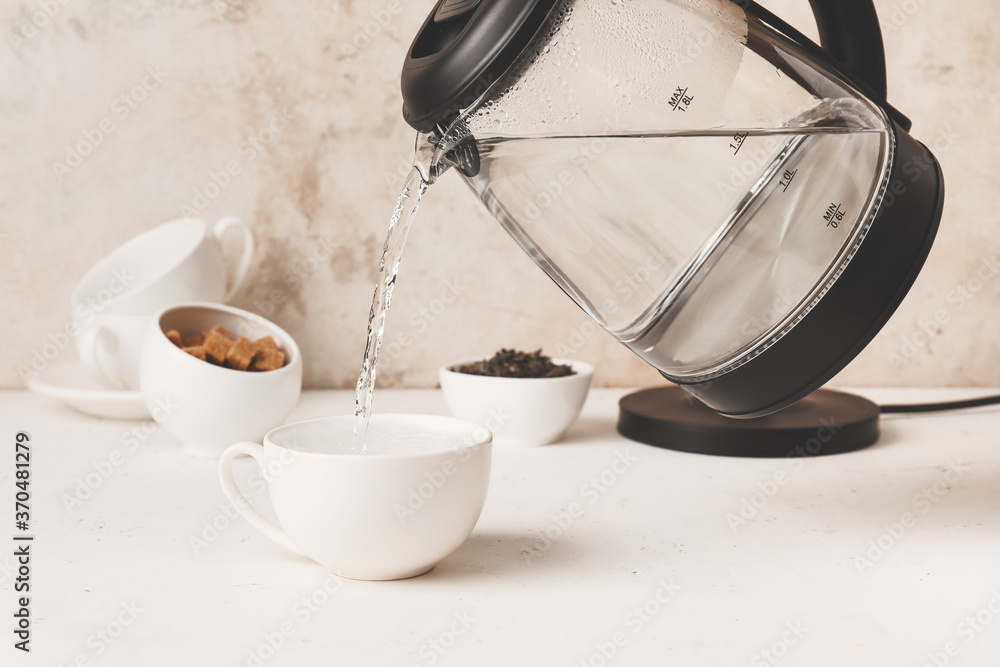 Pouring of hot water in cup on table