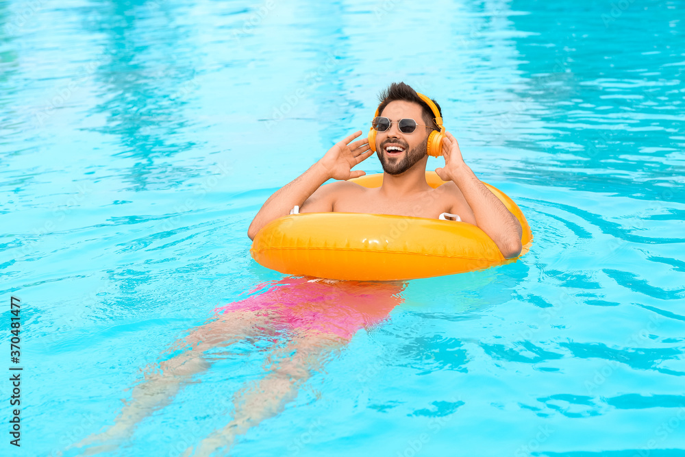 Young man listening to music in swimming pool