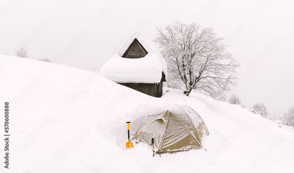 雪山中的木屋和帐篷的极简主义冬季景观。多云，景观