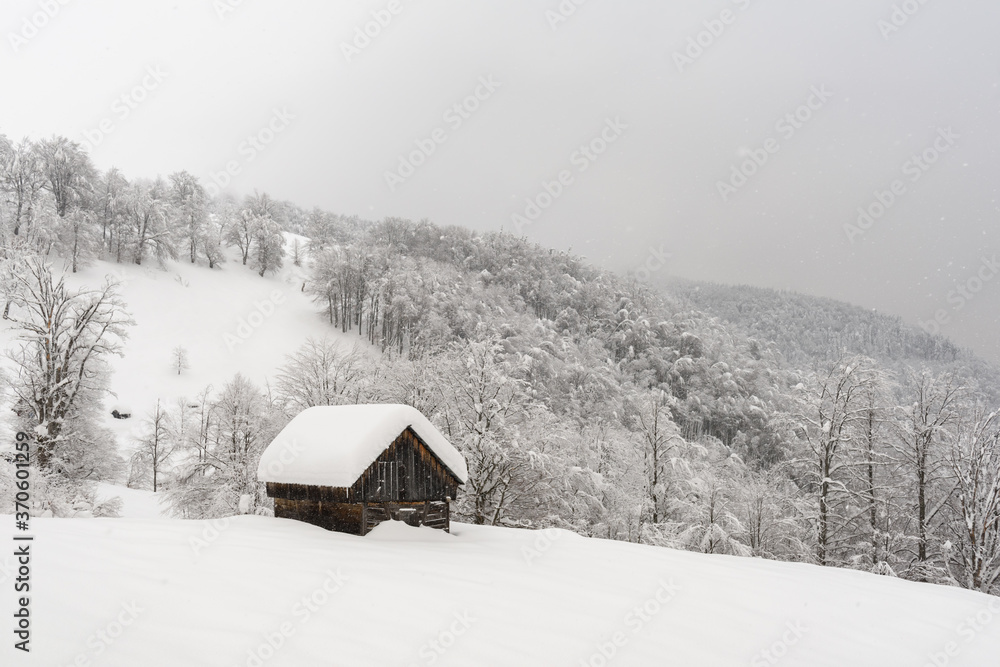 雪山木屋的极简主义冬季景观。多云，景观照片