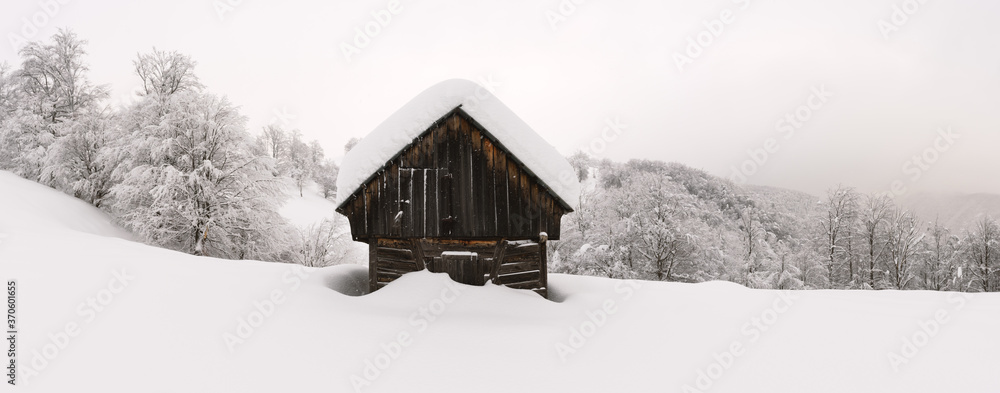 雪山木屋的极简主义冬季景观。多云，景观照片