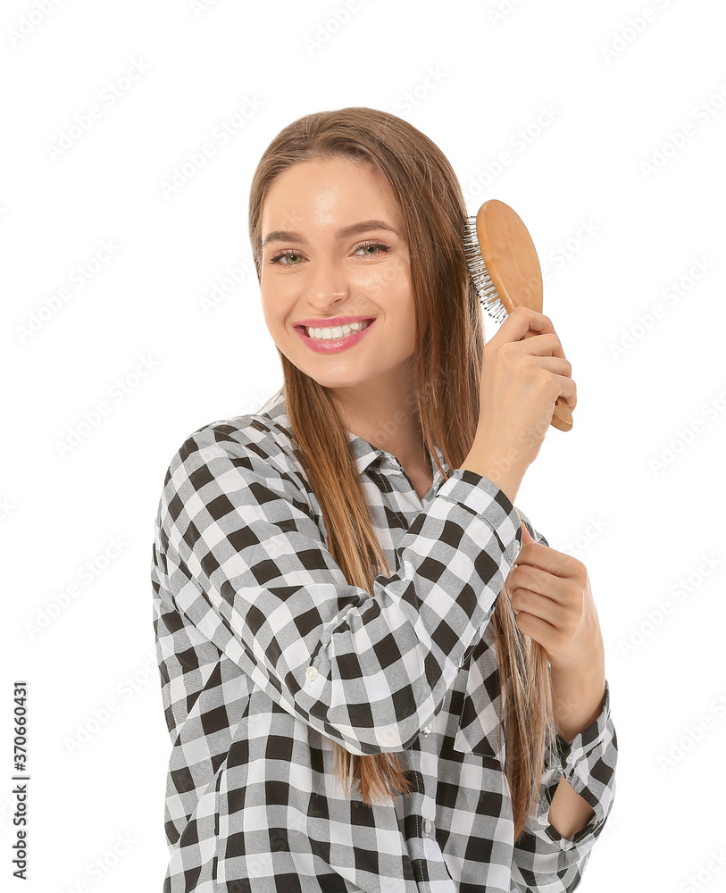 Young woman brushing hair on white background