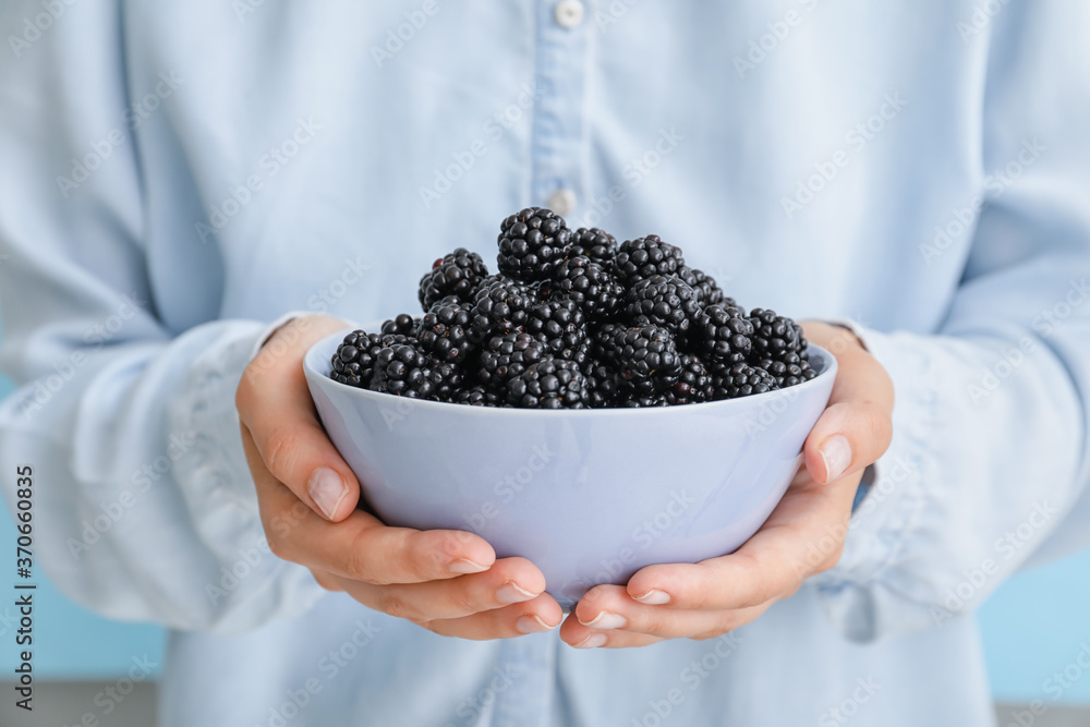 Woman with tasty blackberry in bowl, closeup