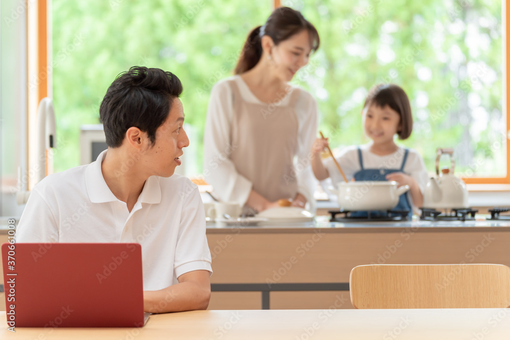 キッチンで働くお父さんと見守る親子