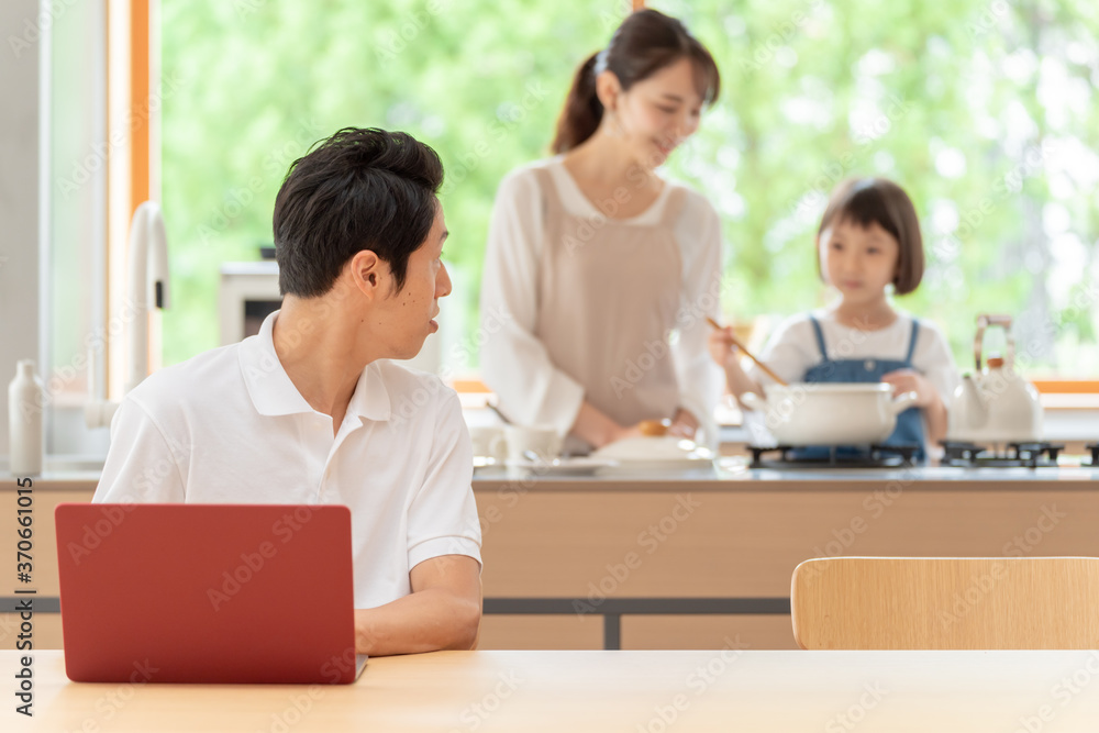 キッチンで働くお父さんと見守る親子