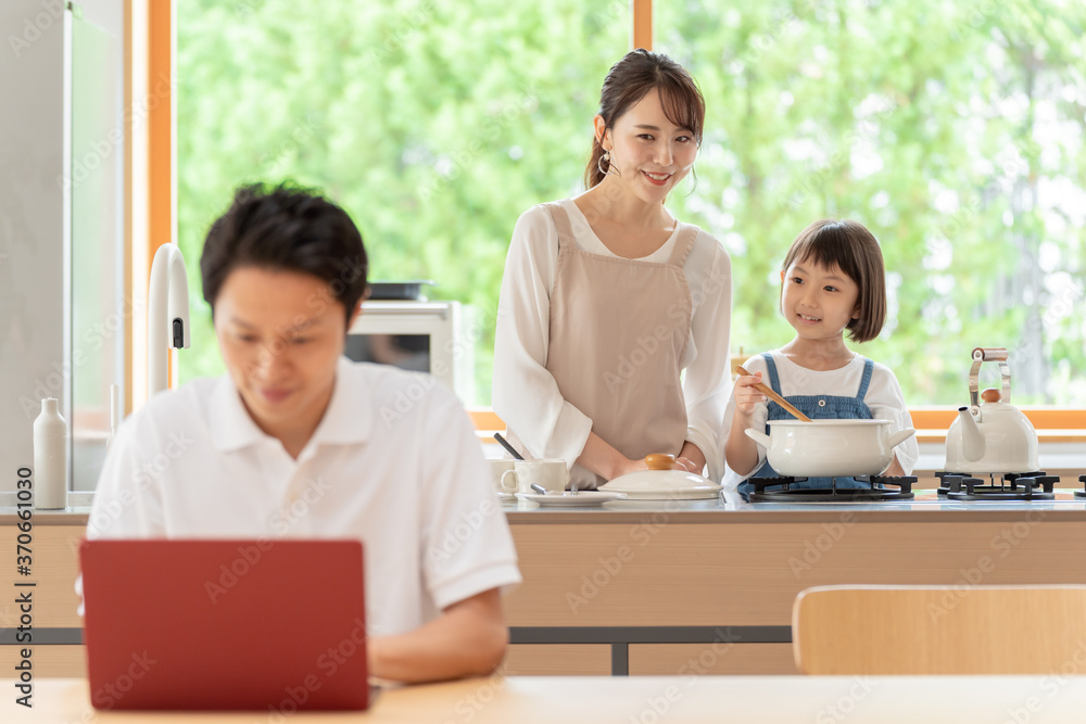 キッチンで働くお父さんと見守る親子