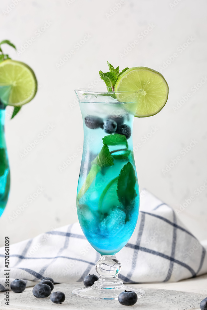 Glass of tasty blue mojito cocktail on white background