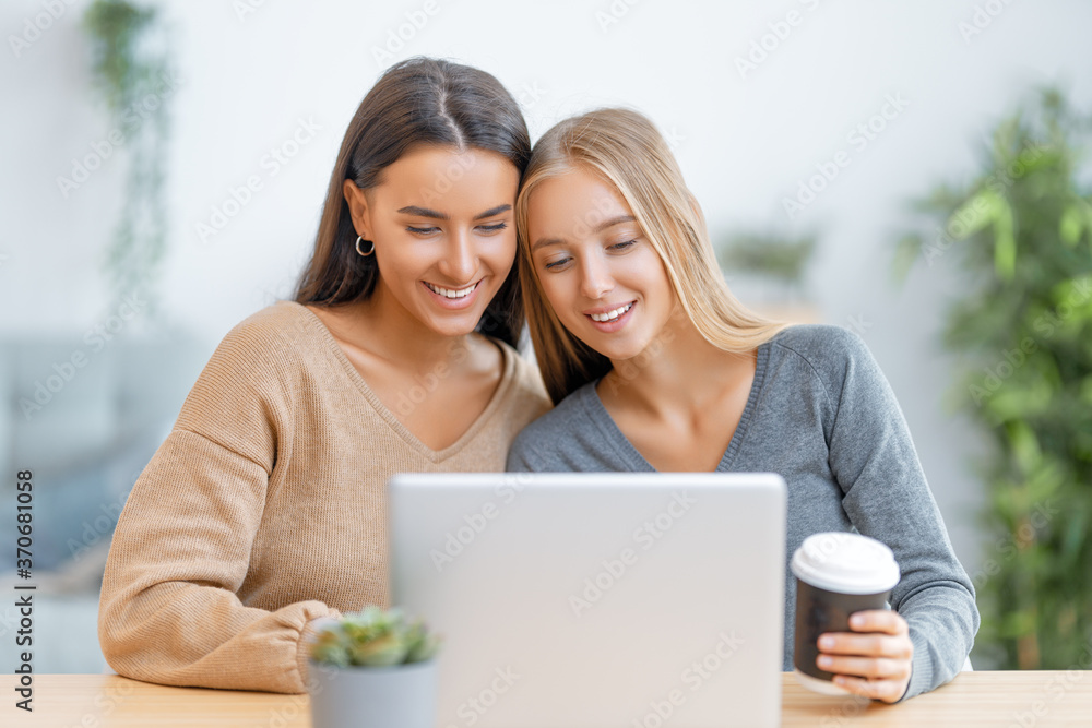 two happy young women using laptop