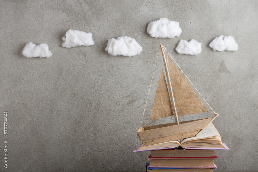 Education is a journey concept, toy boat and books like a sea waves on the wooden table, inspiration