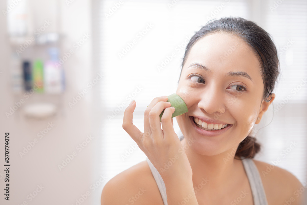 亚洲女人在浴室里把芦荟涂在脸上。