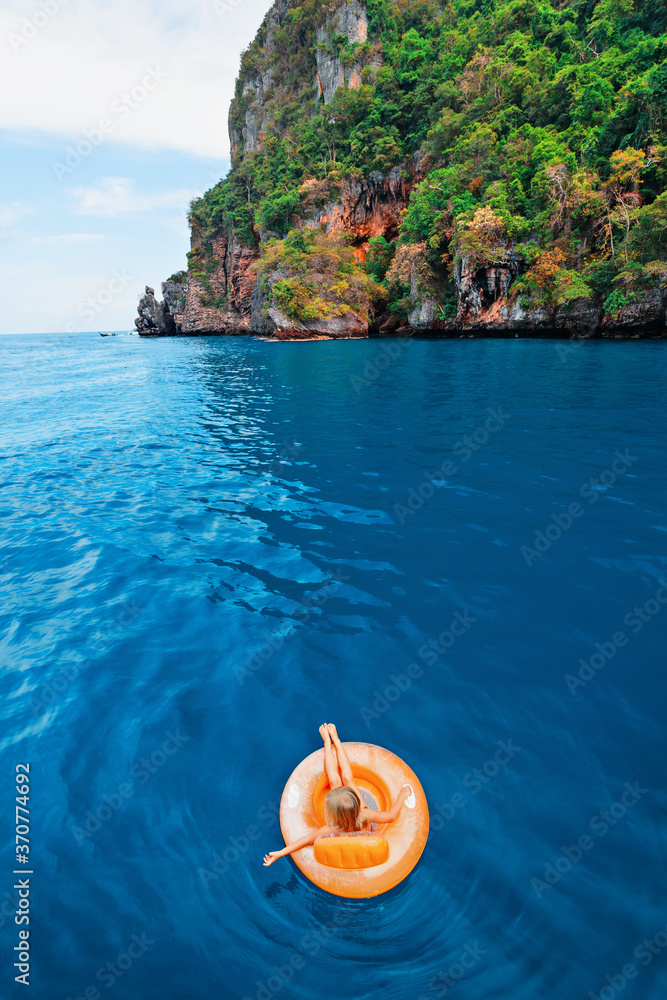 Photo of happy child swimming with fun on inflatable floating ring in sea water pool. Family travel 