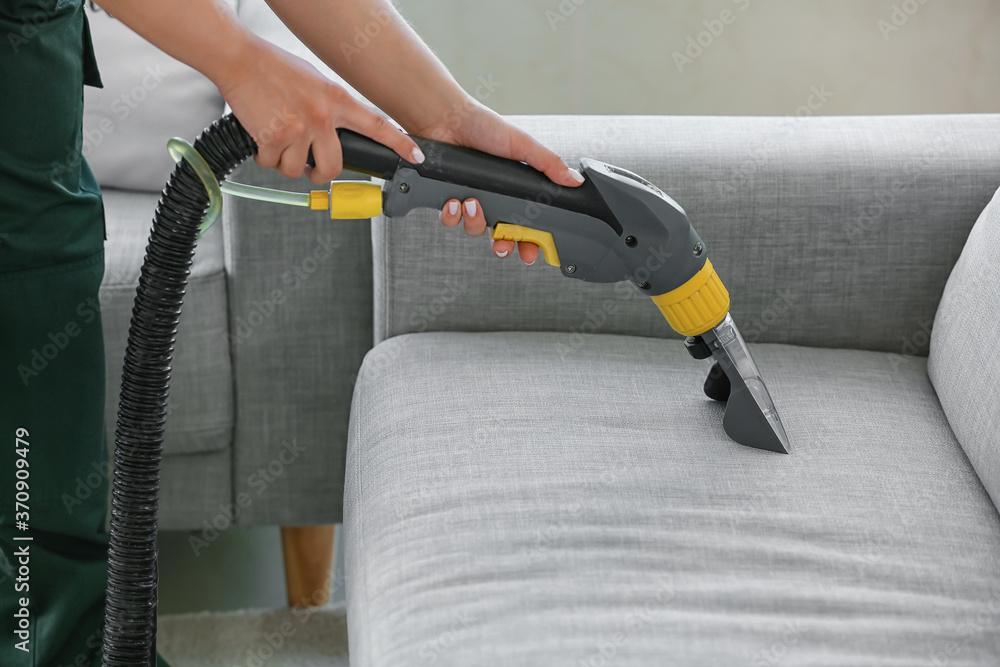 Dry cleaners employee removing dirt from sofa in house