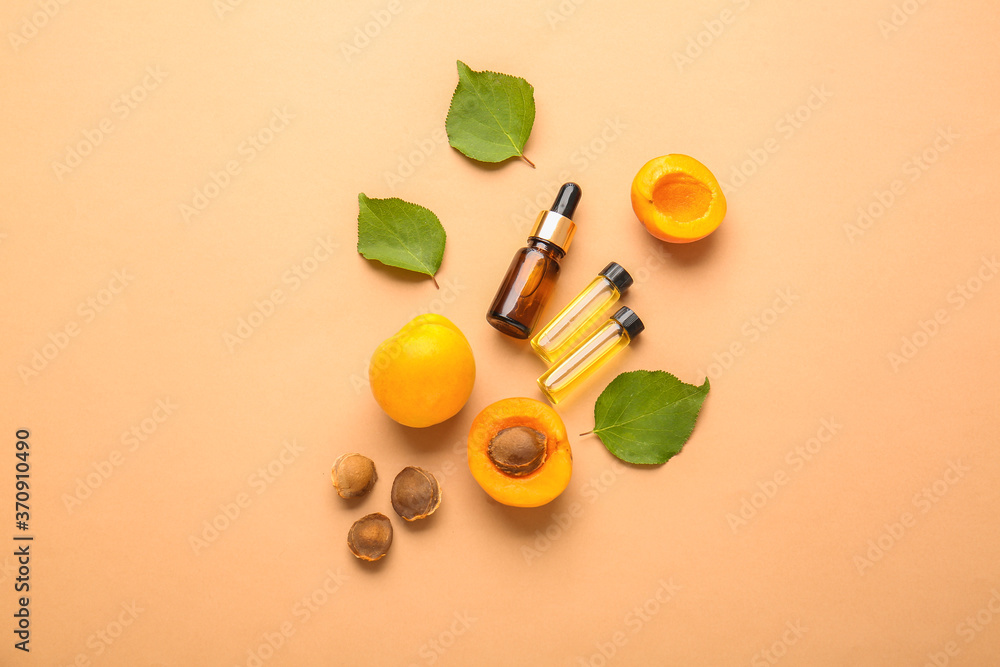 Bottles of apricot essential oil on color background