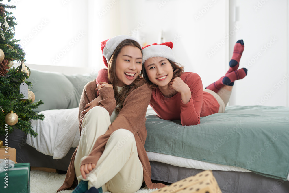 两个漂亮女孩在圣诞树旁等礼物