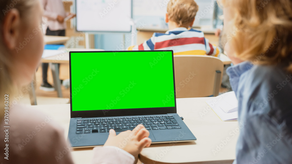 Elementary School Science Class: Over the Shoulder Little Boy and Girl Use Laptop with Green Screen 