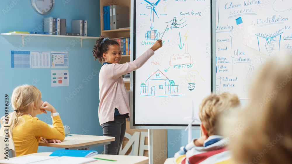 Elementary School Science Class: Cute Girl Uses Interactive Digital Whiteboard to Show to a Classroo