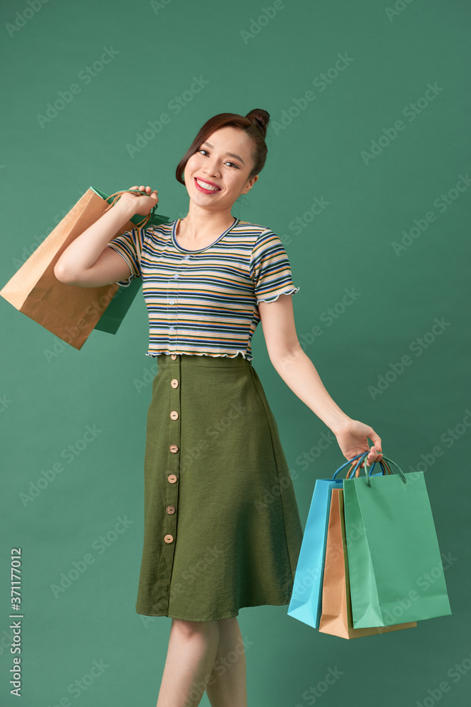 Stylish asian woman smiling and holding shopping bags