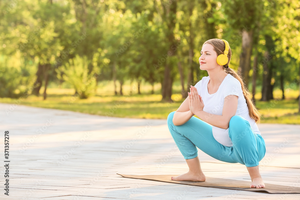 Young pregnant woman practicing yoga outdoors