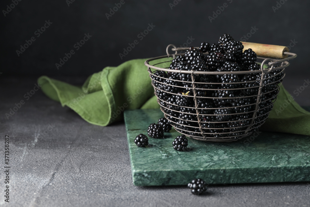 Basket with tasty blackberry on dark background