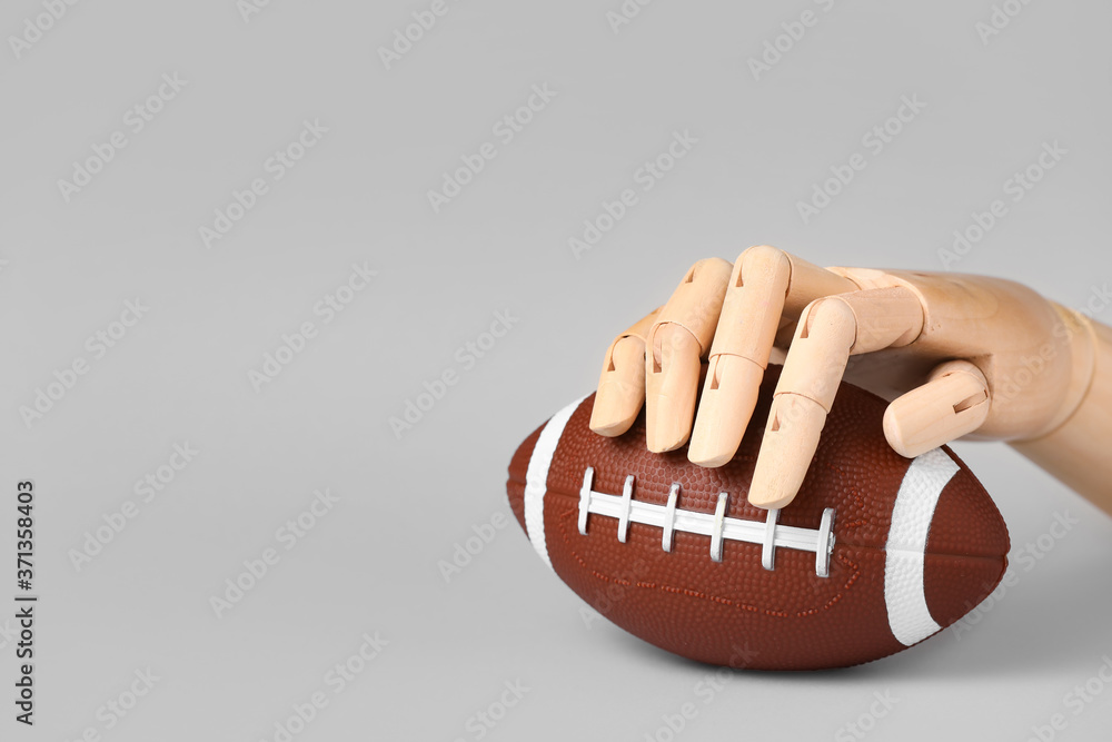 Hand of mannequin with rugby ball on grey background