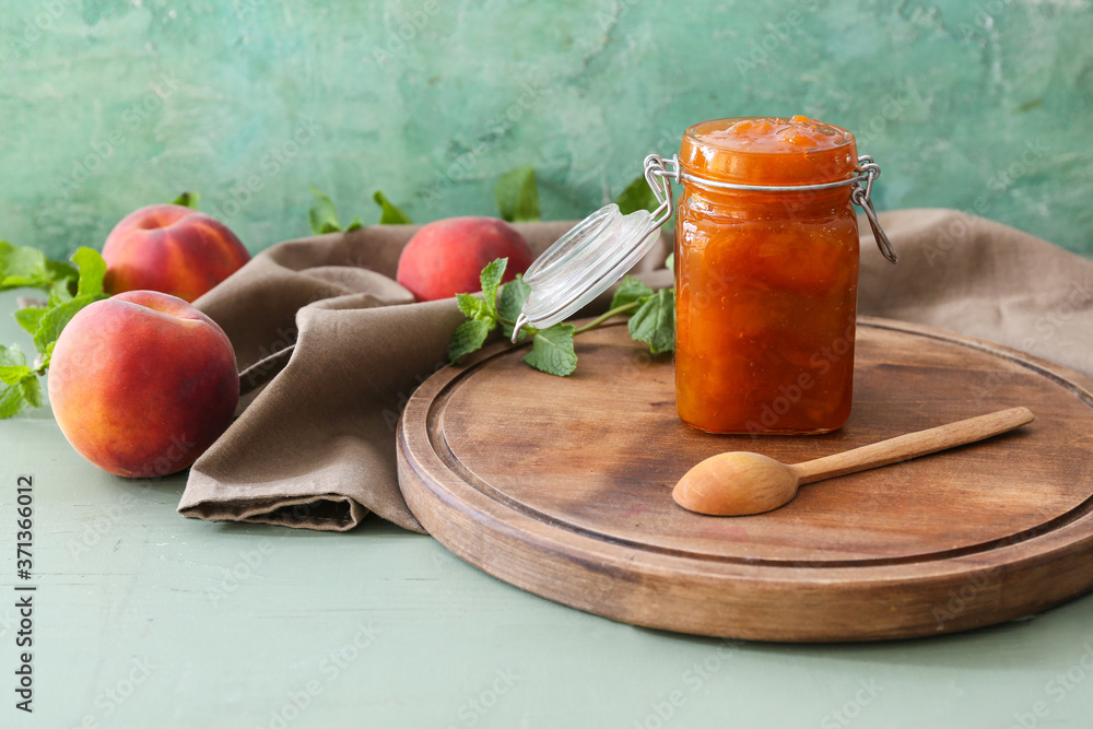 Jar with tasty peach jam on table