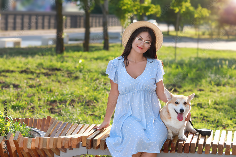 带着可爱的柯基犬在户外散步的女人