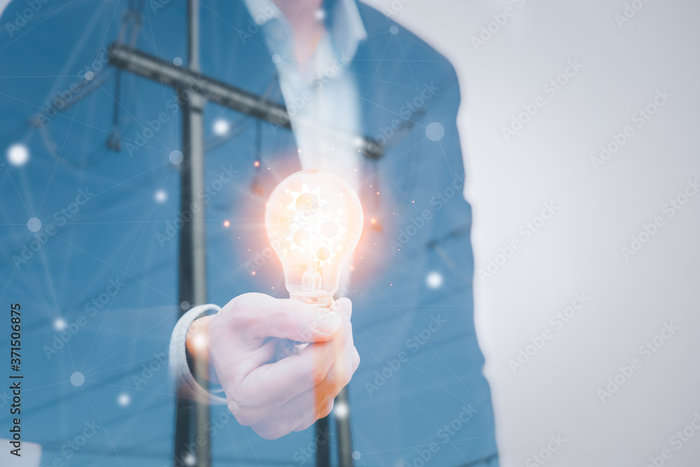 Double exposure of businessman holding the light bulb in the background of an electric pole Energy p