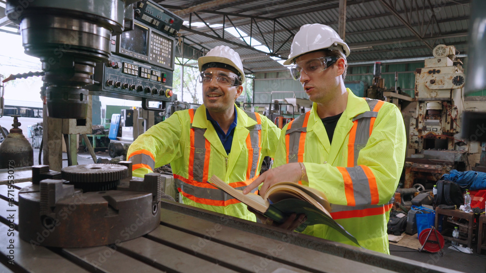 Group of factory workers using machine equipment in factory workshop . Industry and engineering conc