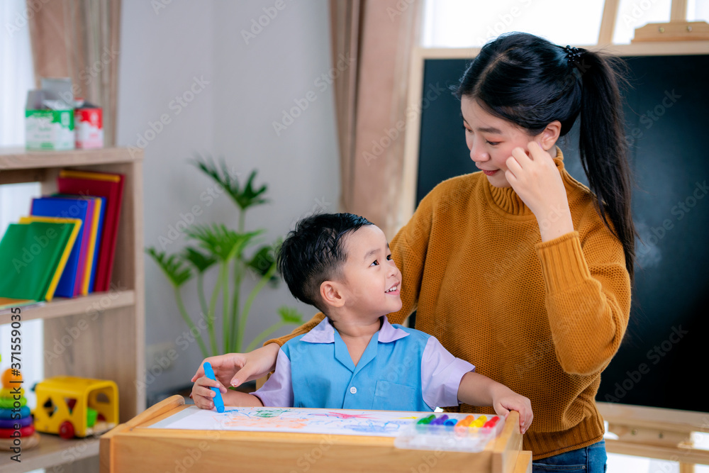 幼儿园教室里的亚洲老师教学生画画