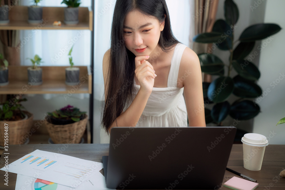 一名亚洲女孩在电脑笔记本上输入数据，准备她关于木deak的报告