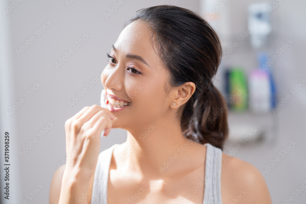 Beautiful female brushing teeth in the bathroom