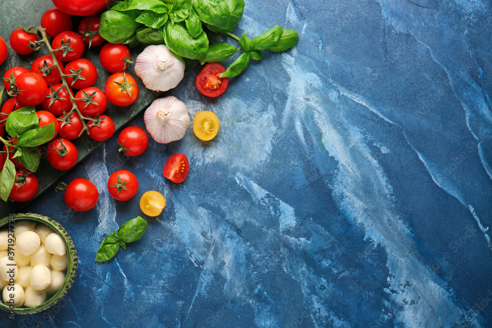 Composition with fresh cherry tomatoes, garlic, basil and mozzarella cheese on color background