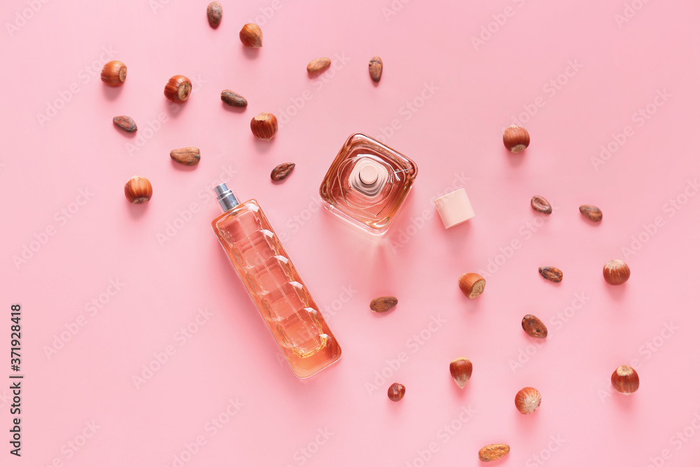 Bottles of perfumes and coffee beans on color background