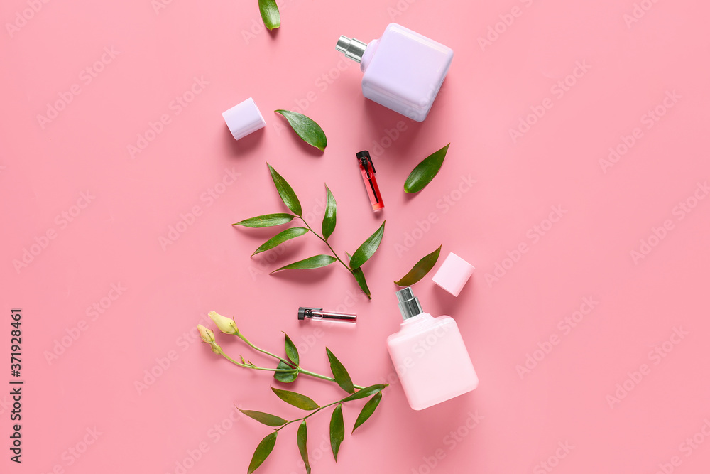 Bottles of floral perfumes on color background