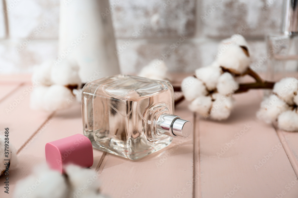 Bottle of perfume and cotton branch on table