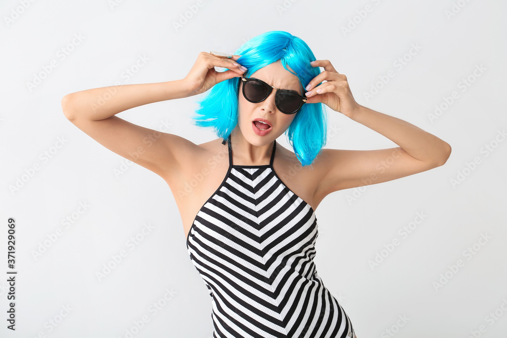 Beautiful young woman in wig on light background