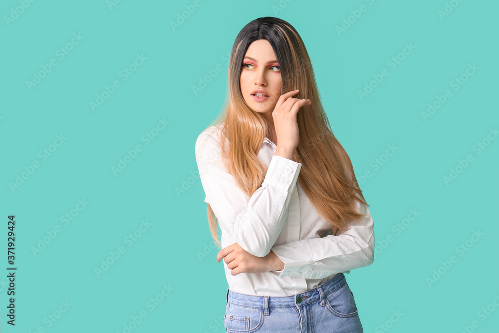 Beautiful young woman in wig on color background