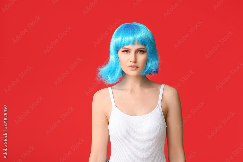 Beautiful young woman in wig on color background