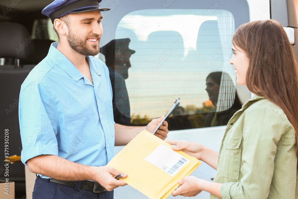 Woman receiving letter from postman outdoors