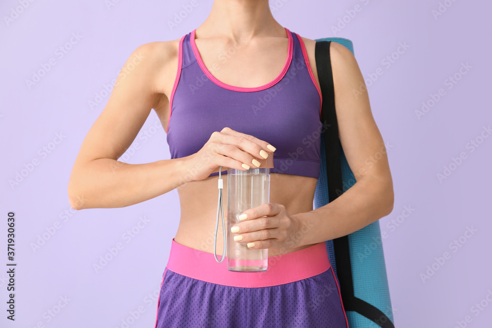 Sporty young woman with bottle of water on color background