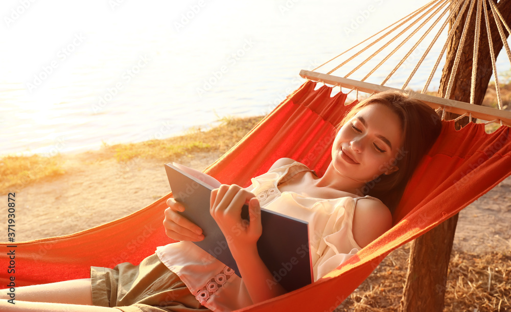 Young woman reading book while relaxing in hammock outdoors