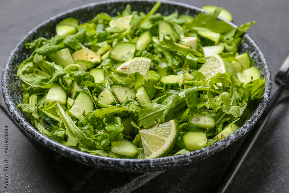 Plate with tasty cucumber salad on dark background