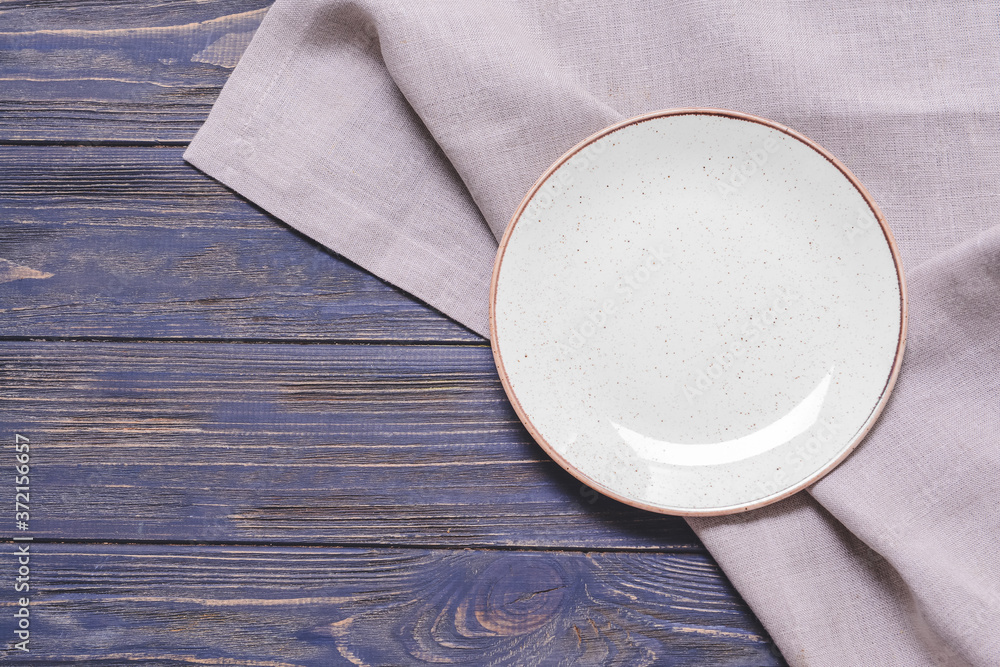 Clean plate with napkin on wooden background