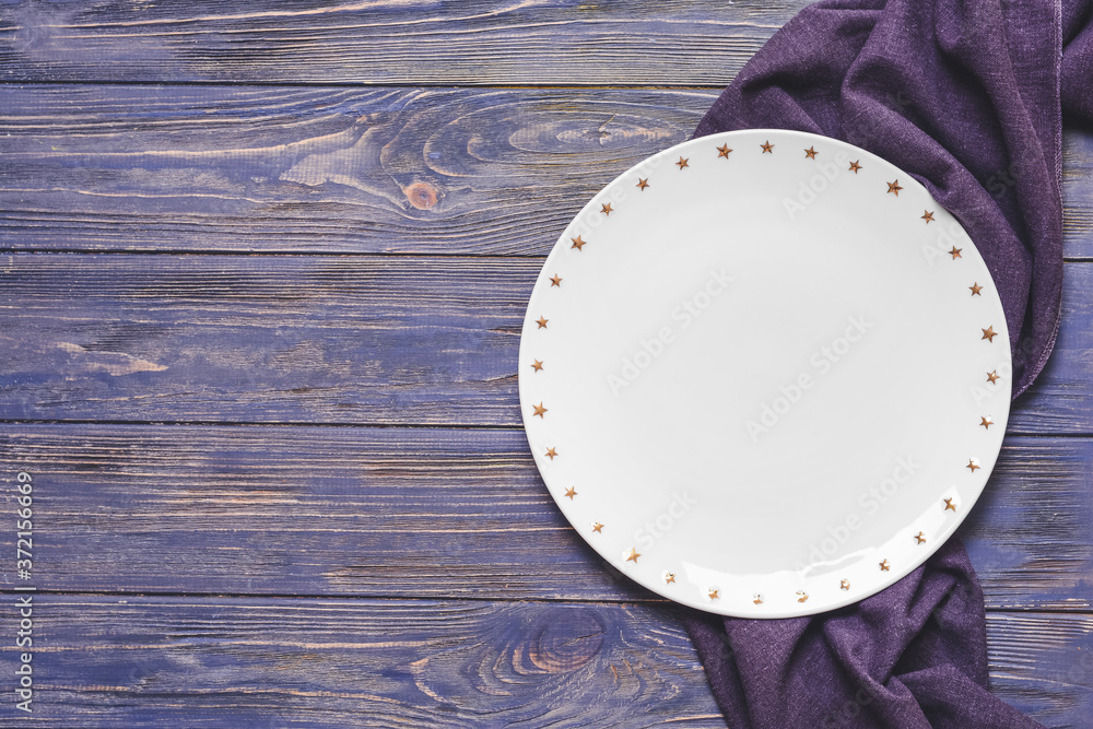 Clean plate with napkin on wooden background