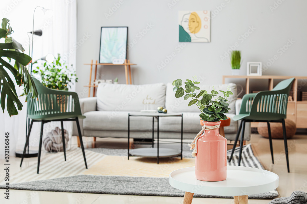 Vase with floral decor on table in interior of living room